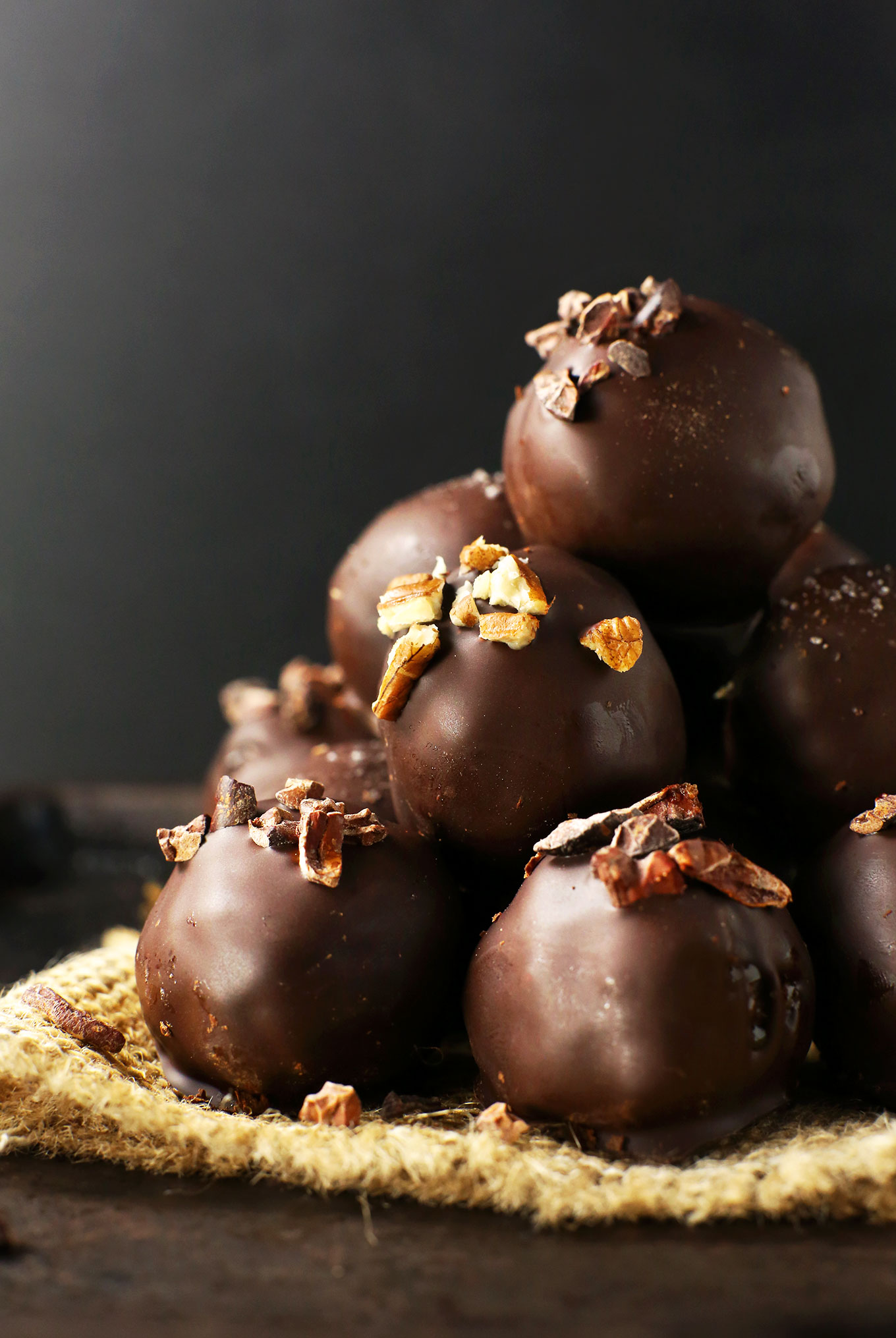 Pile of healthy Vegan Chocolate Truffles topped with pecans and cacao nibs