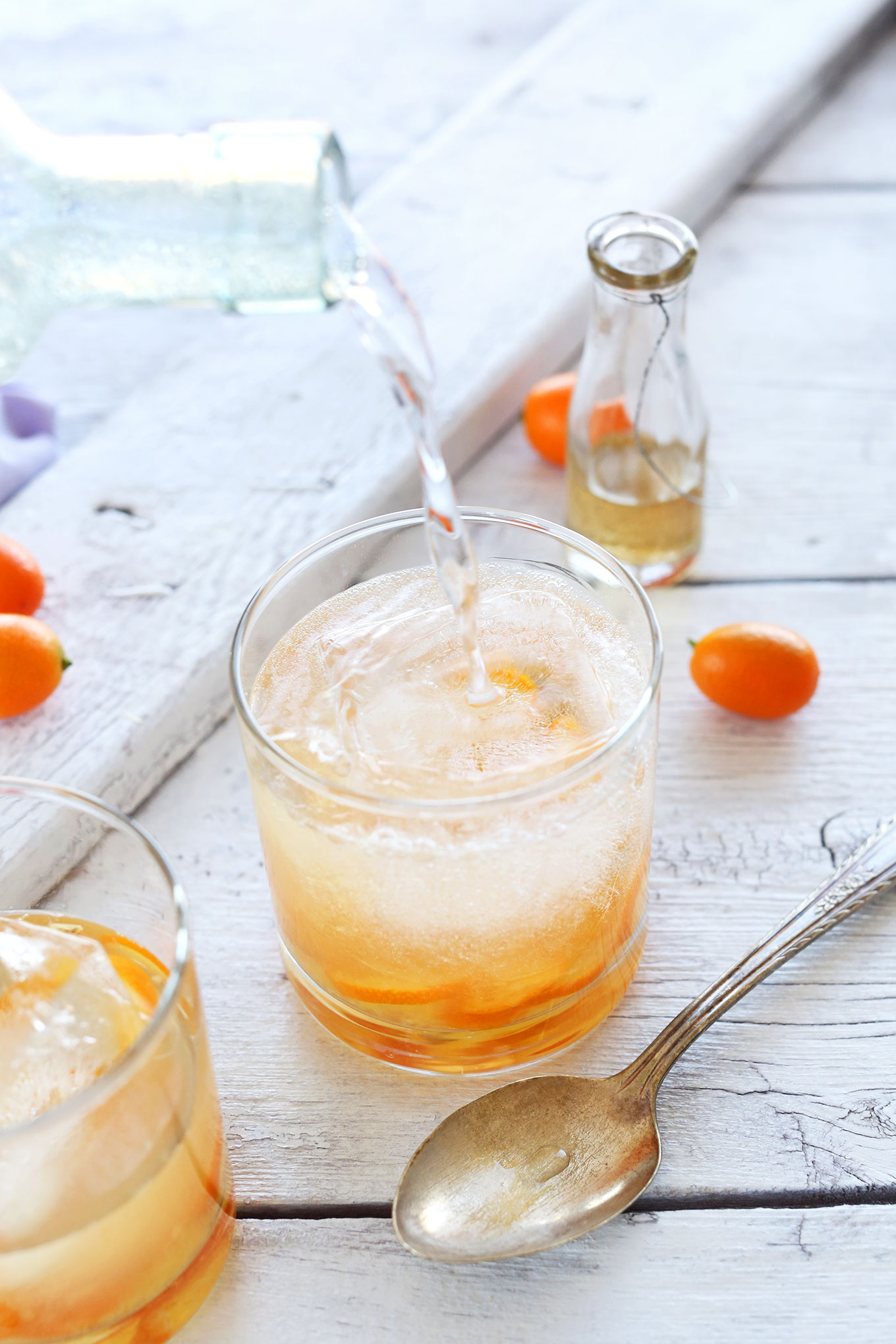 Pouring sparkling water into a glass to make our All Natural Citrus Gin and Tonics recipe