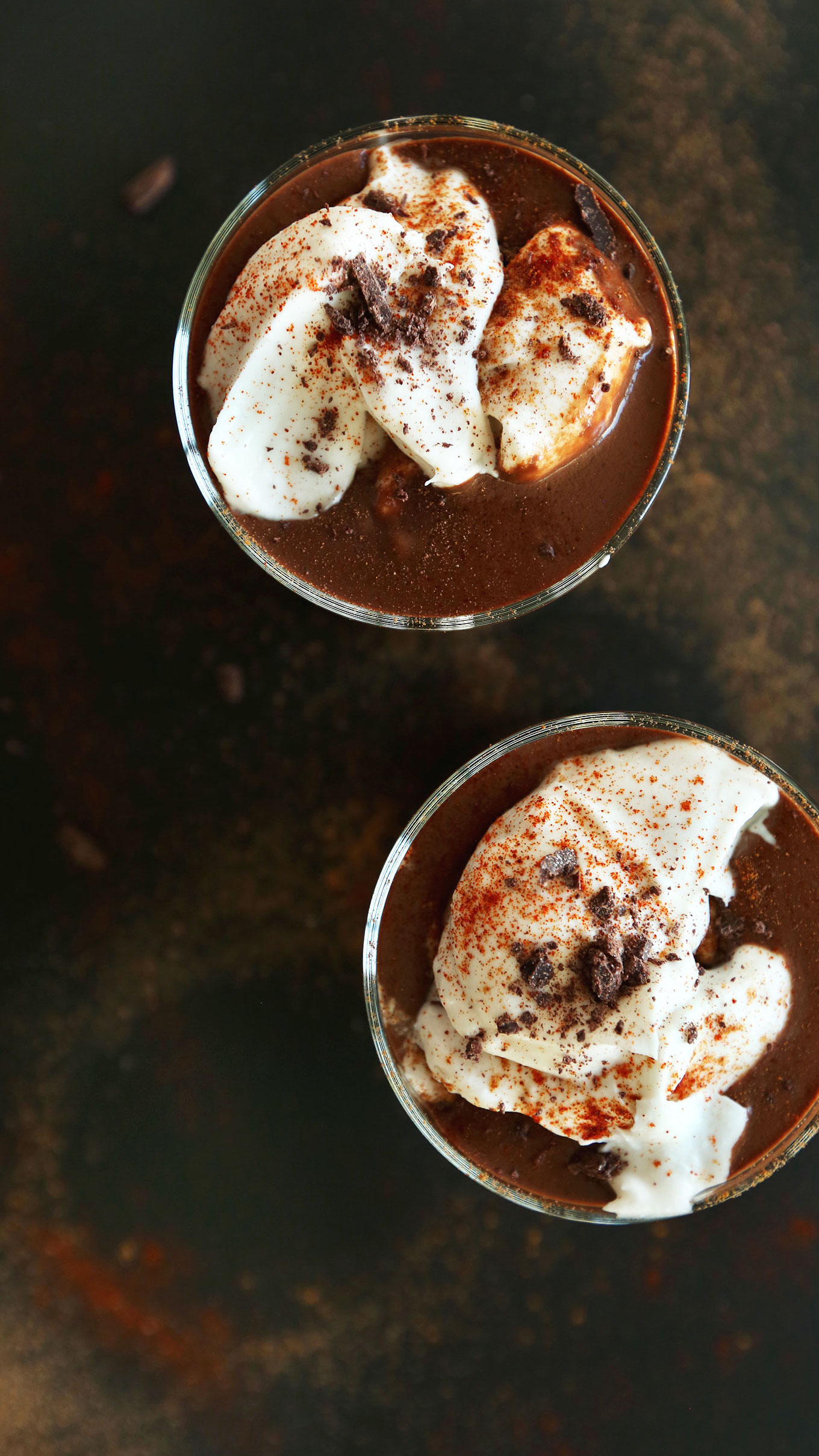Two glasses of simple vegan Mayan Drinking Chocolate topped with coconut whip and shaved chocolate