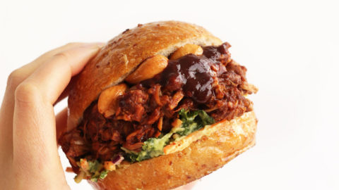 Holding up a healthy gluten-free vegan BBQ Jackfruit Sandwich