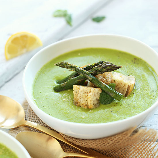 Bowl of Creamy Asparagus and Pea Soup topped with croutons and asparagus spears