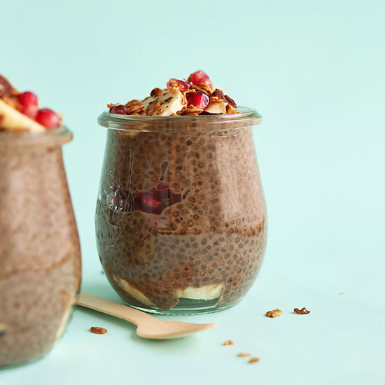 Small jars of Chocolate Chia Seed Pudding topped with pomegranate, banana, and granola