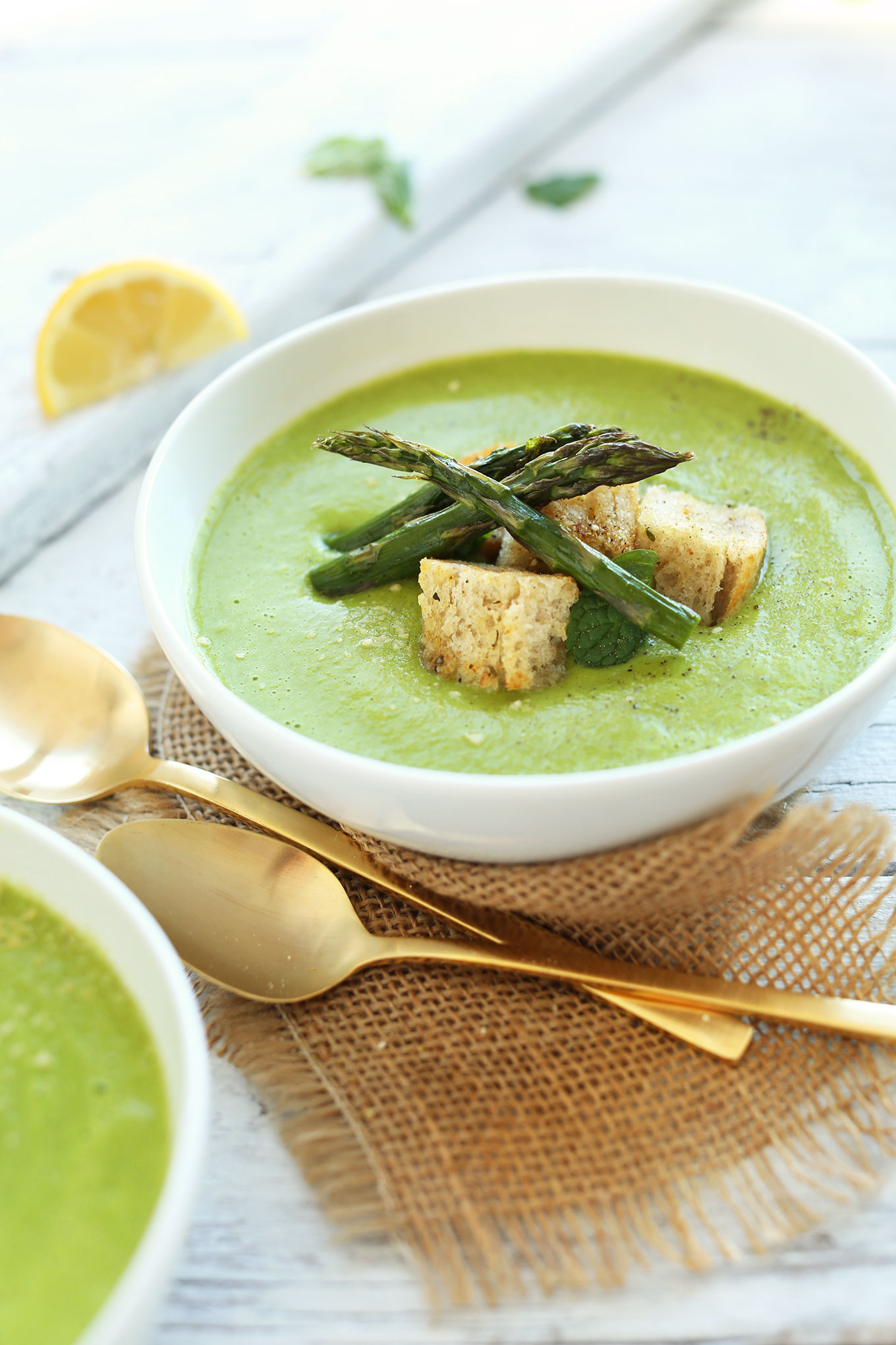 Bowl of Creamy vegan Asparagus and Pea Soup topped with croutons and asparagus spears