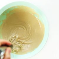 Whisking a bowl of homemade Maple Tahini Dressing for adding to kale salad