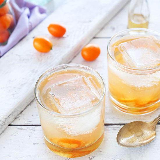 Kumquats and ice cubes in glasses filled with our homemade Gin and Tonic recipe