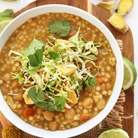 Bowl of green chickpea curry topped with cabbage and cilantro