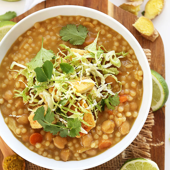 Bowl of green chickpea curry topped with cabbage and cilantro