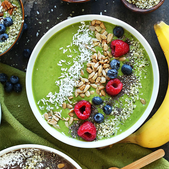 Vibrant Green Smoothie Bowl topped with shredded coconut, sunflower seeds, berries, chia seeds, and hemp seeds