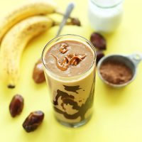 Tall glass of our PB Banana Shake surrounded by ingredients to make it