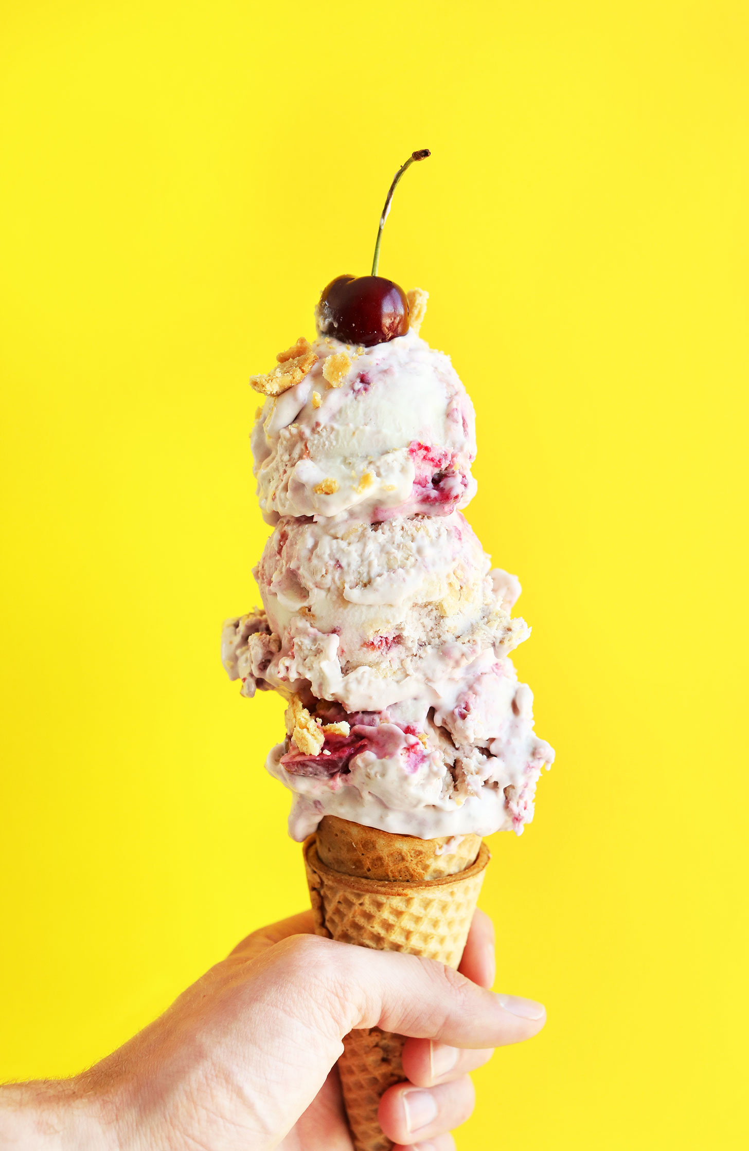 Scoops of our Vegan Cherry Pie Ice Cream on a sugar cone