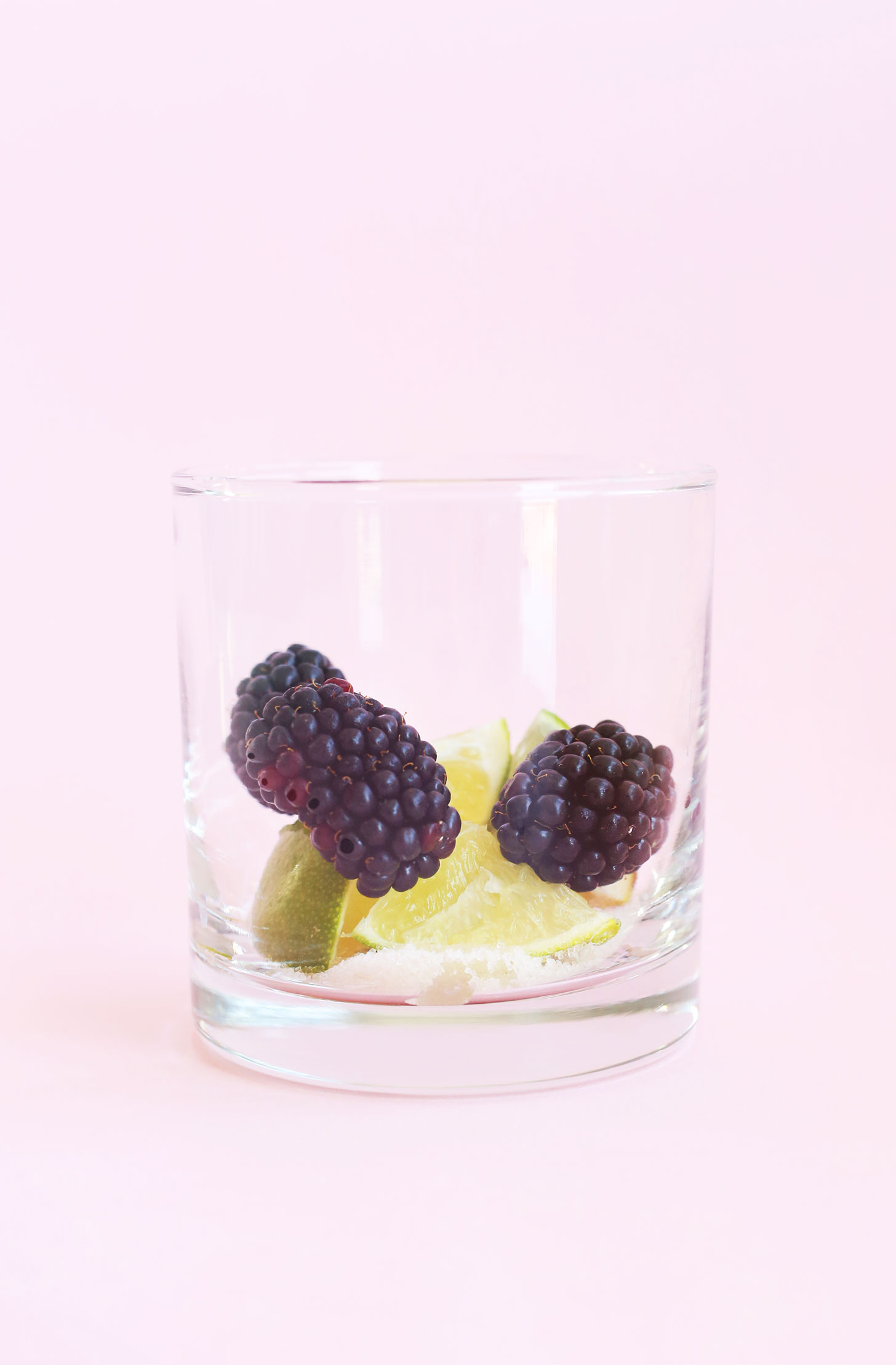 Cocktail glass with blackberries and lime wedges for homemade mojitos