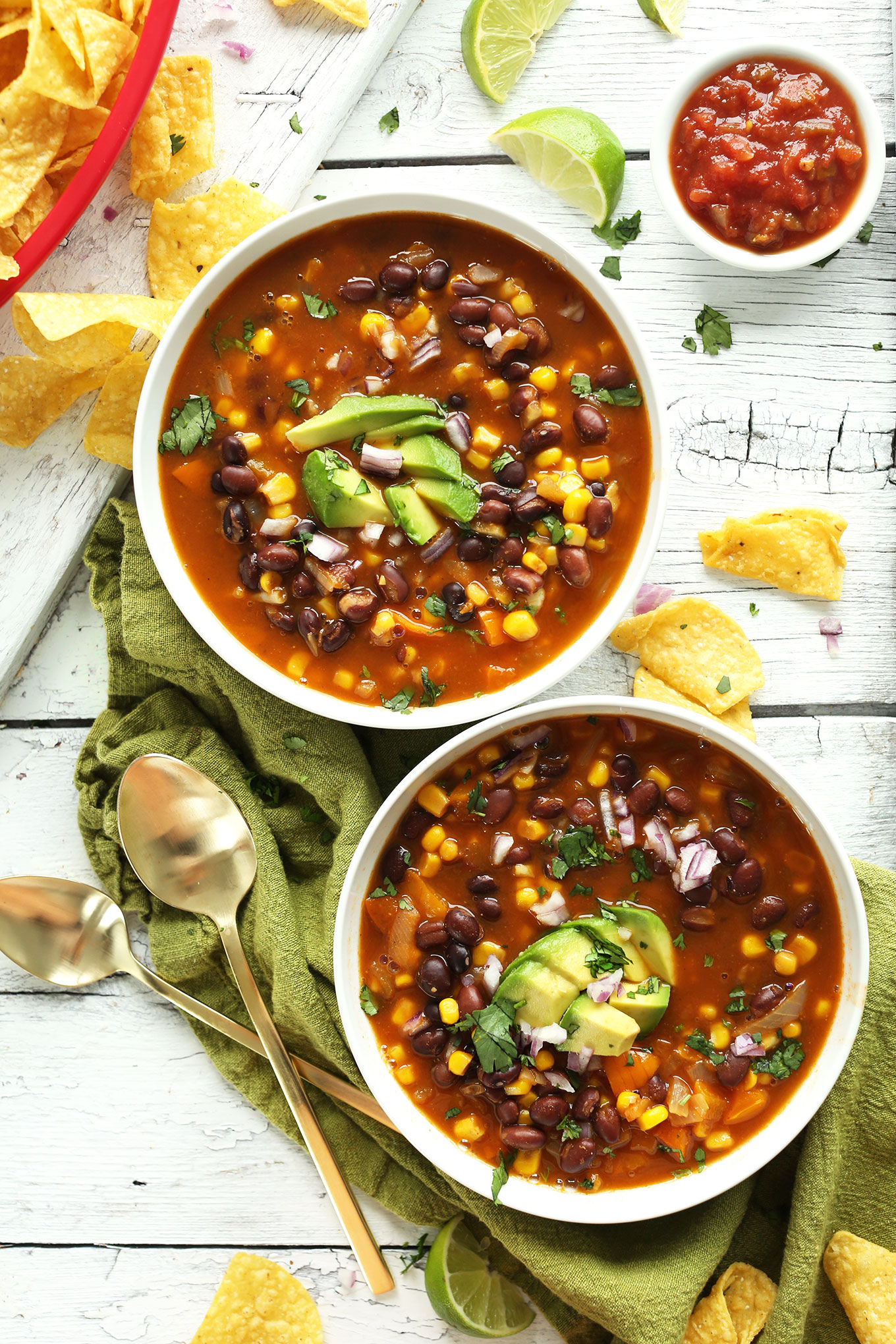 Two bowls of delicious vegan Black Bean Tortilla Soup topped with avocado and red onion