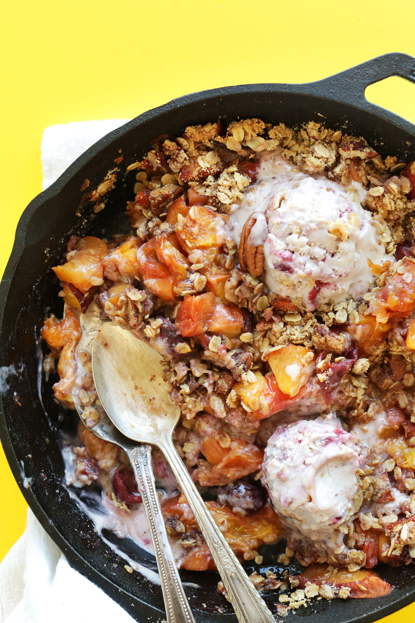 Cast-iron skillet with our Summer Peach Crisp with scoops of dairy-free ice cream