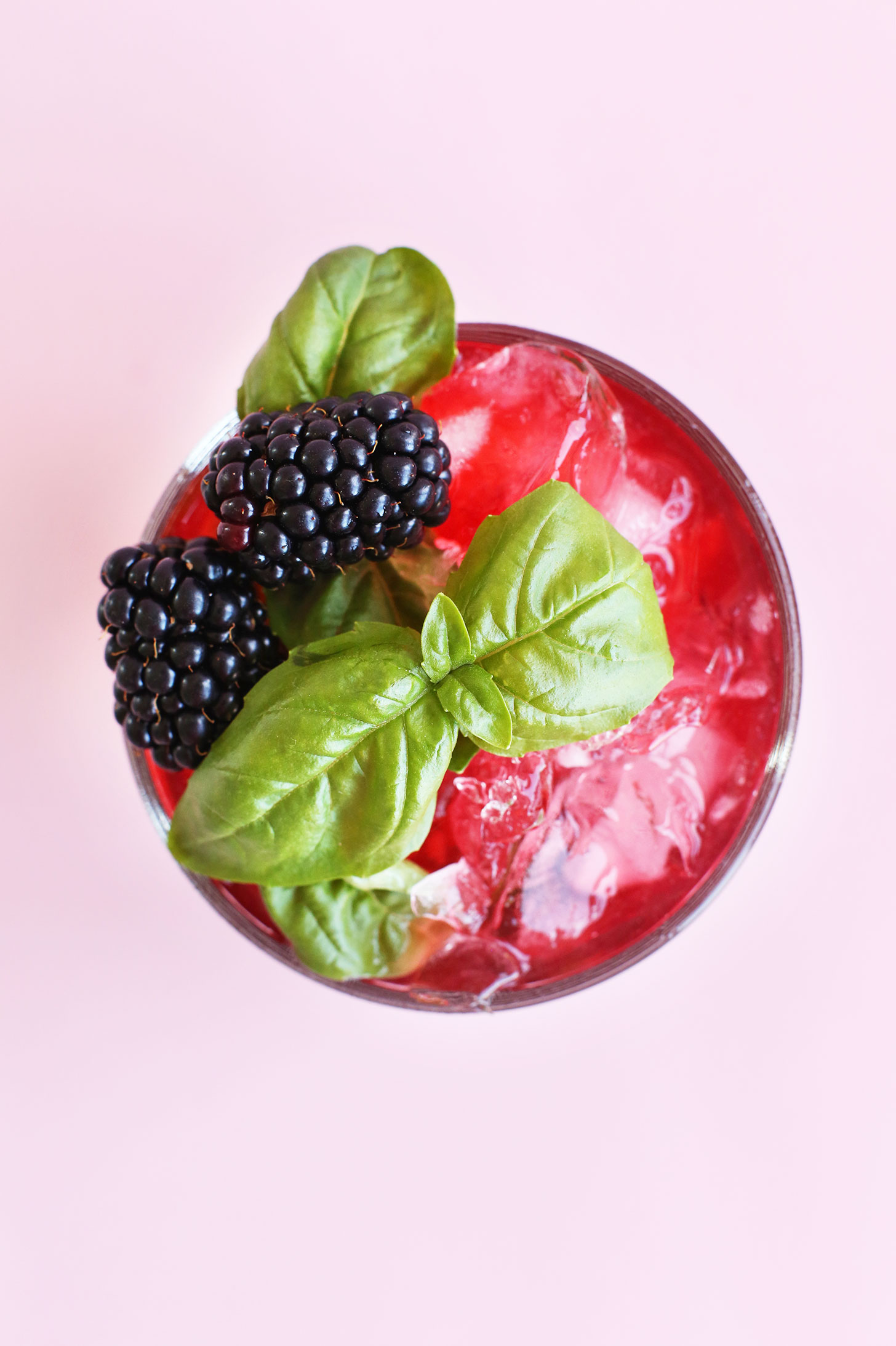 Top down shot showing fresh blackberries and basil on a summery drink