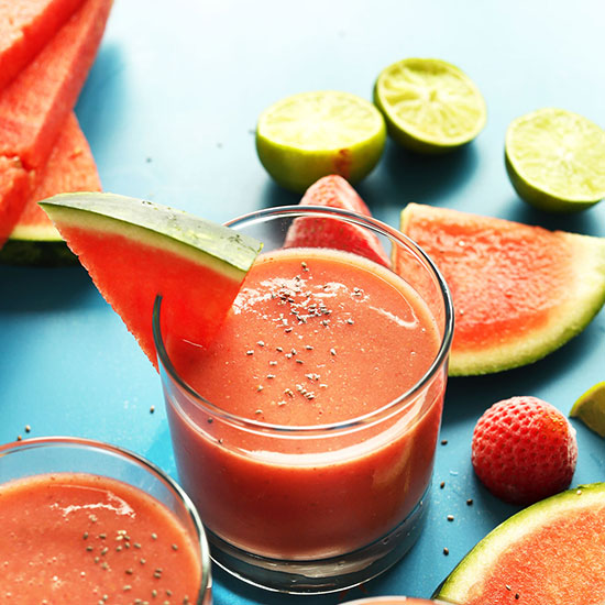 Two short glasses of our Strawberry Watermelon Smoothie recipe beside ingredients used to make it