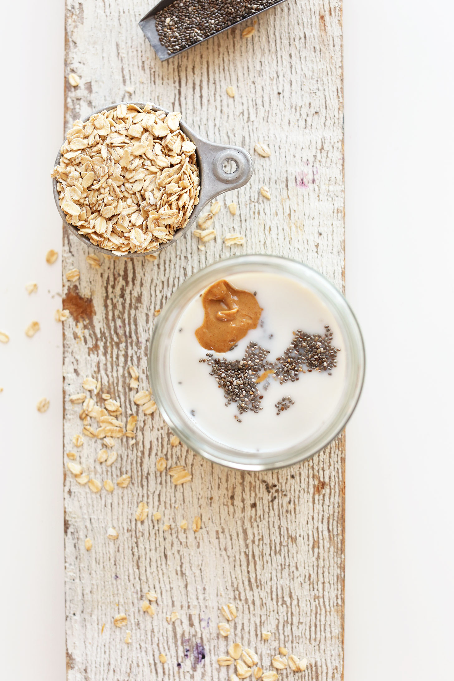 Jar of Peanut Butter Overnight Oats alongside oats and chia seeds for a fiber-rich vegan breakfast