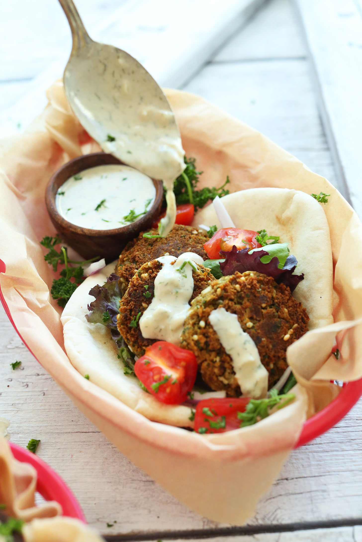 Pouring delicious vegan Mediterranean-style dressing over falafel