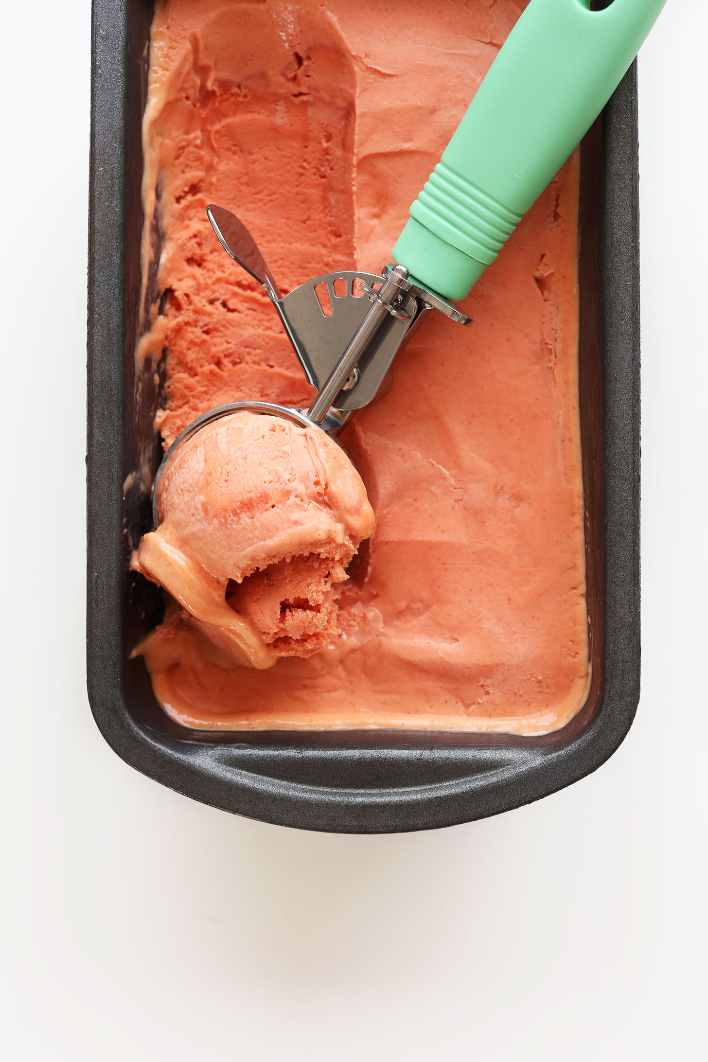Using an ice cream scooper to grab a scoop of delicious homemade Mango Raspberry Coconut Sorbet