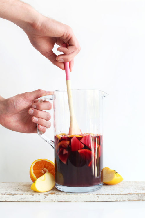 Stirring pitcher of Traditional Red Sangria for a refreshing vegan summer drink