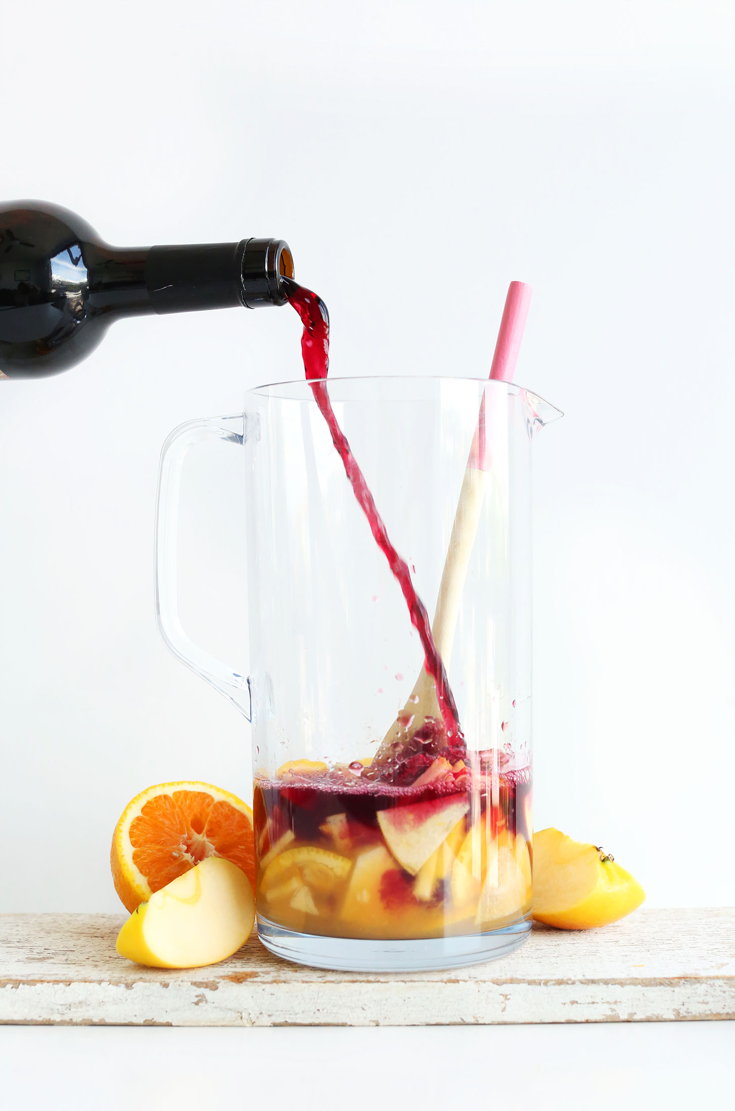Pouring red wine into a pitcher for our homemade Traditional Red Sangria recipe