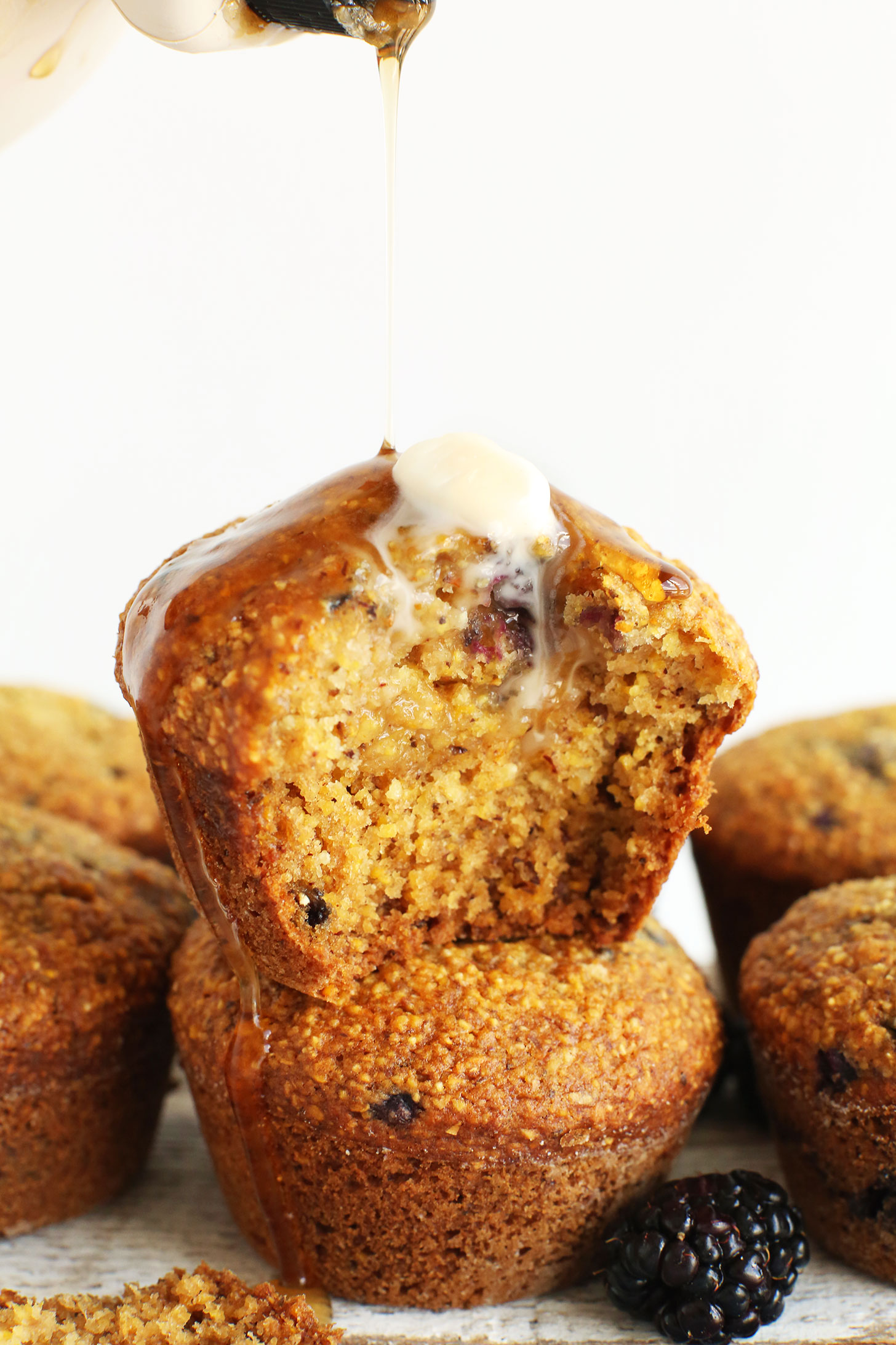 Pouring syrup onto an amazing Blackberry Cornmeal Muffin