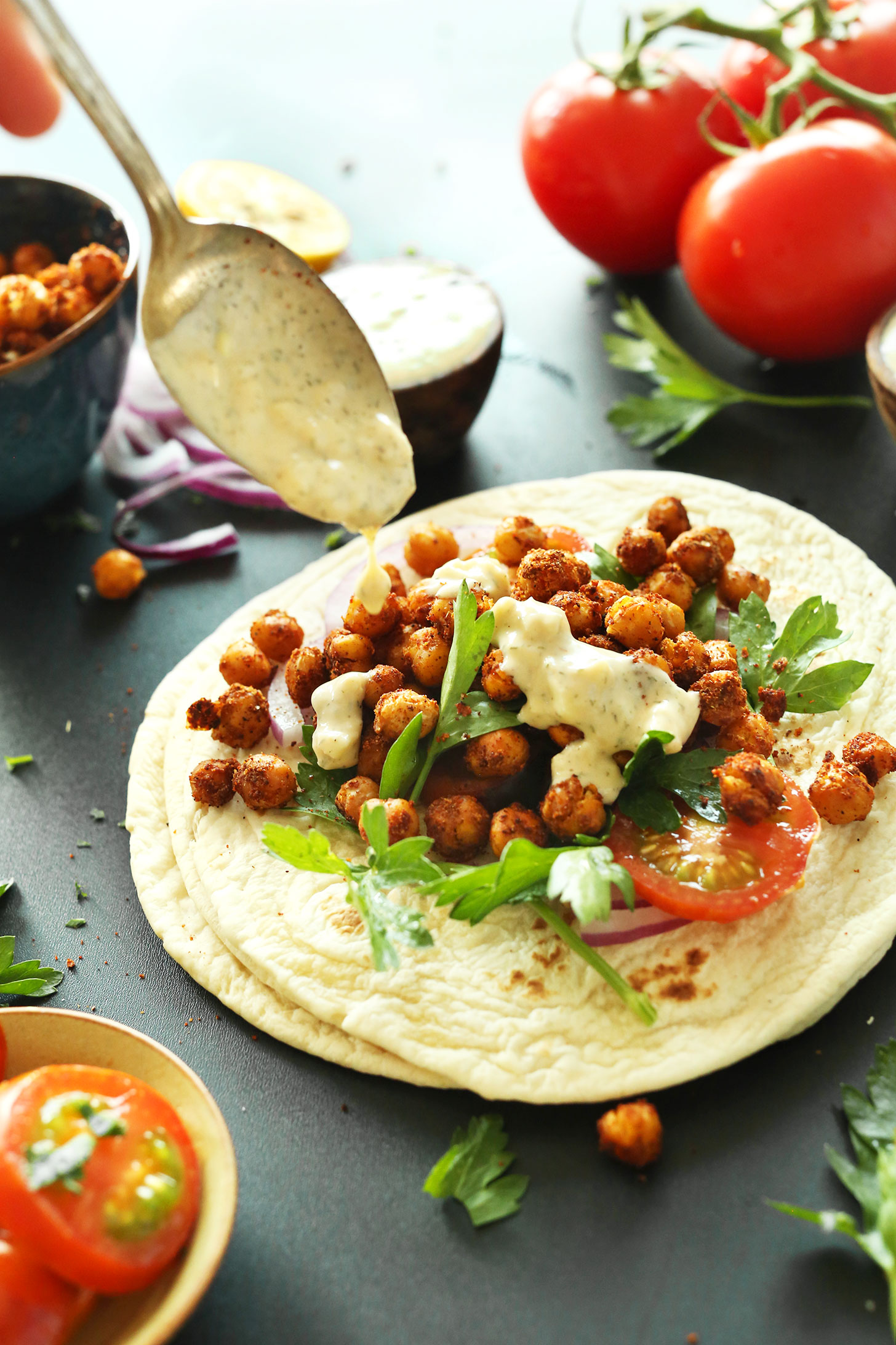 Drizzling Garlic Dill Sauce over Chickpea Shawarma Wraps for delicious vegan flavor