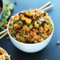 Chopsticks beside a bowl of Vegan Fried Rice topped with tofu