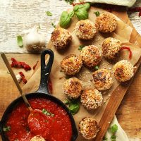 Platter of our healthy Vegan Arancini with a cast-iron skillet of warm marinara
