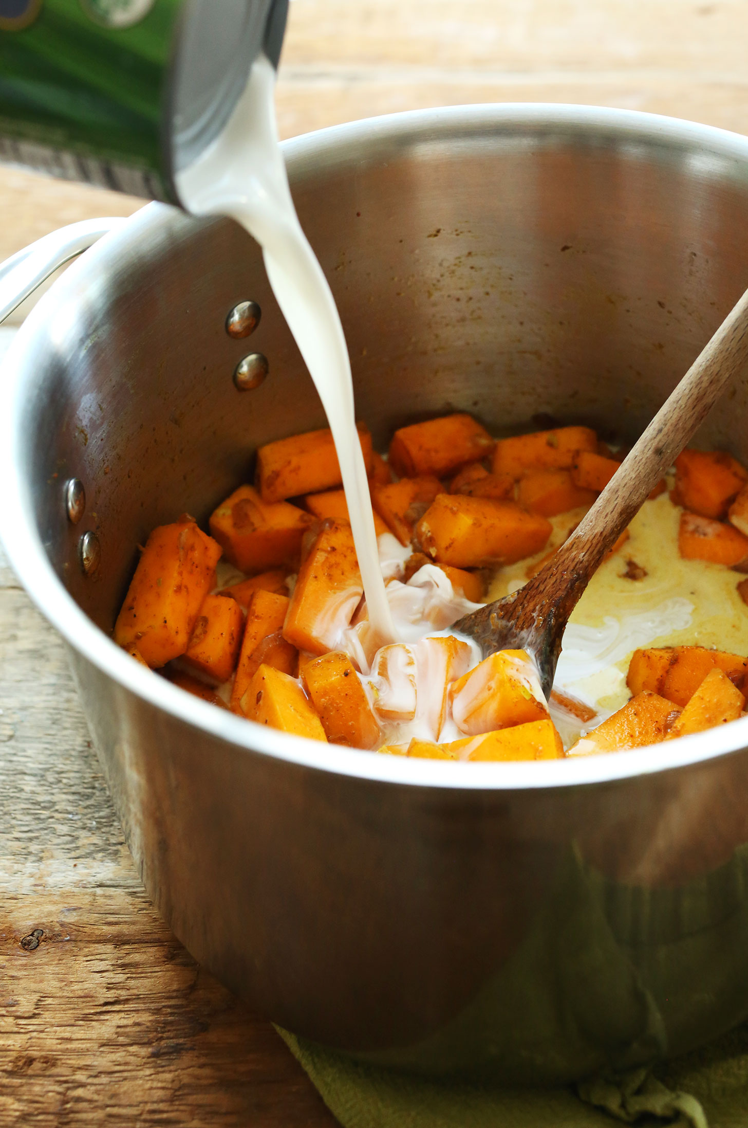 Adding coconut milk to our Curried Butternut Squash Soup for a creamy vegan soup recipe