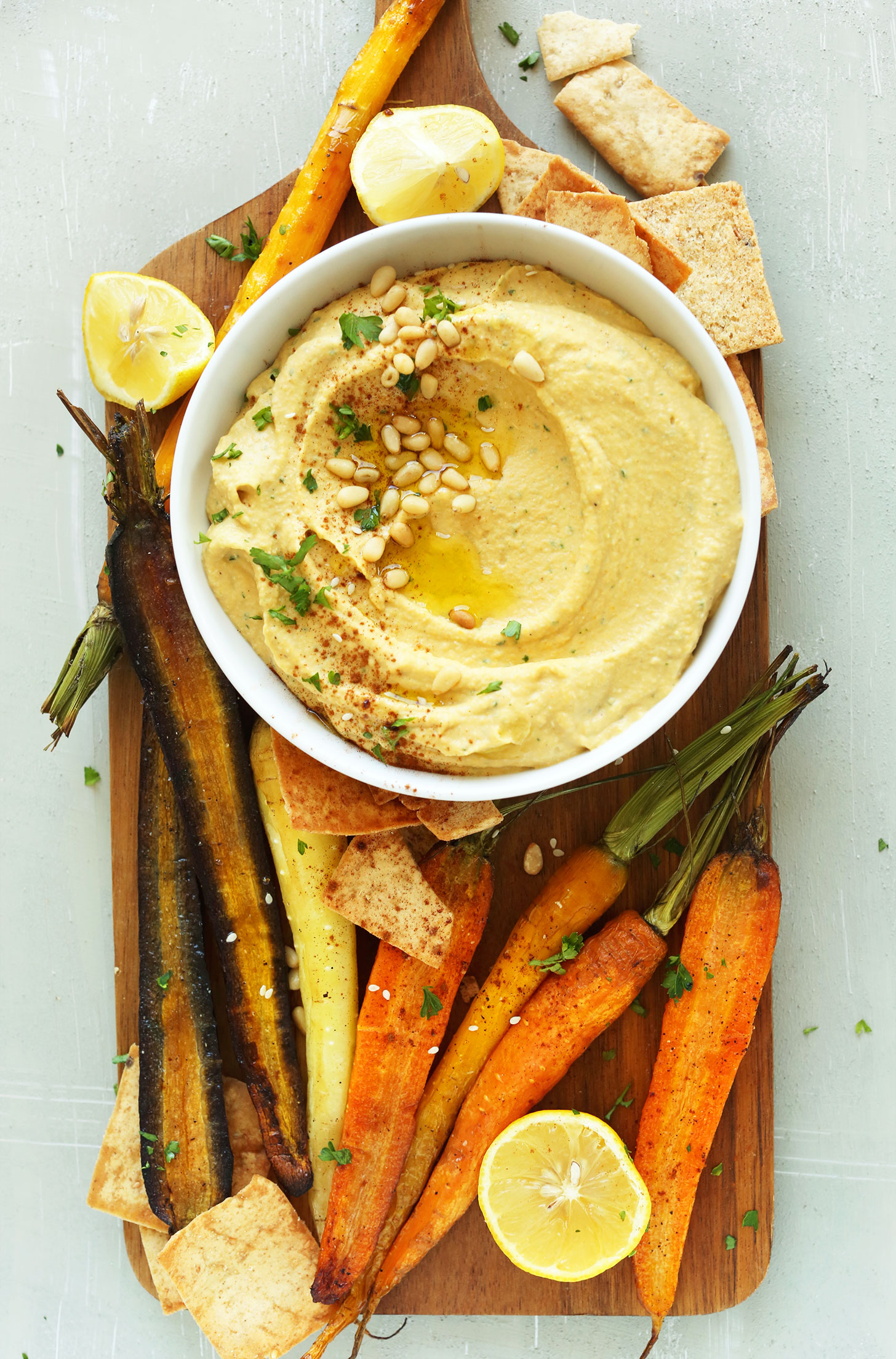 Wood platter with a bowl of gluten-free vegan Butternut Squash Hummus and goodies for dipping