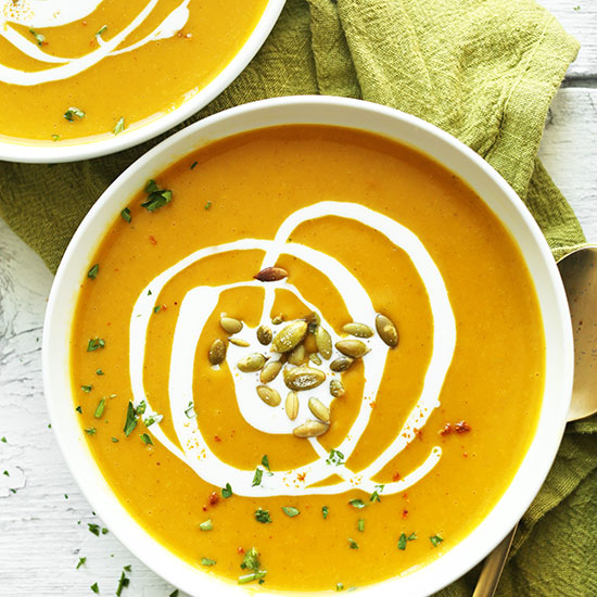 Bowls of Curried Butternut Squash Soup topped with pepitas and a coconut milk drizzle