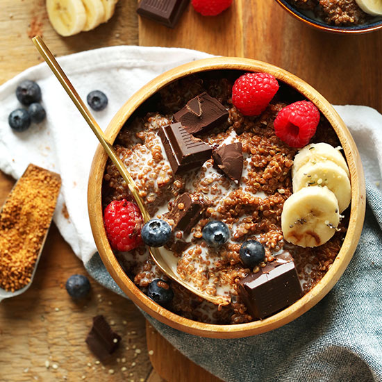 Wood bowl of our Dark Chocolate Quinoa Breakfast Bowl topped with fresh fruit