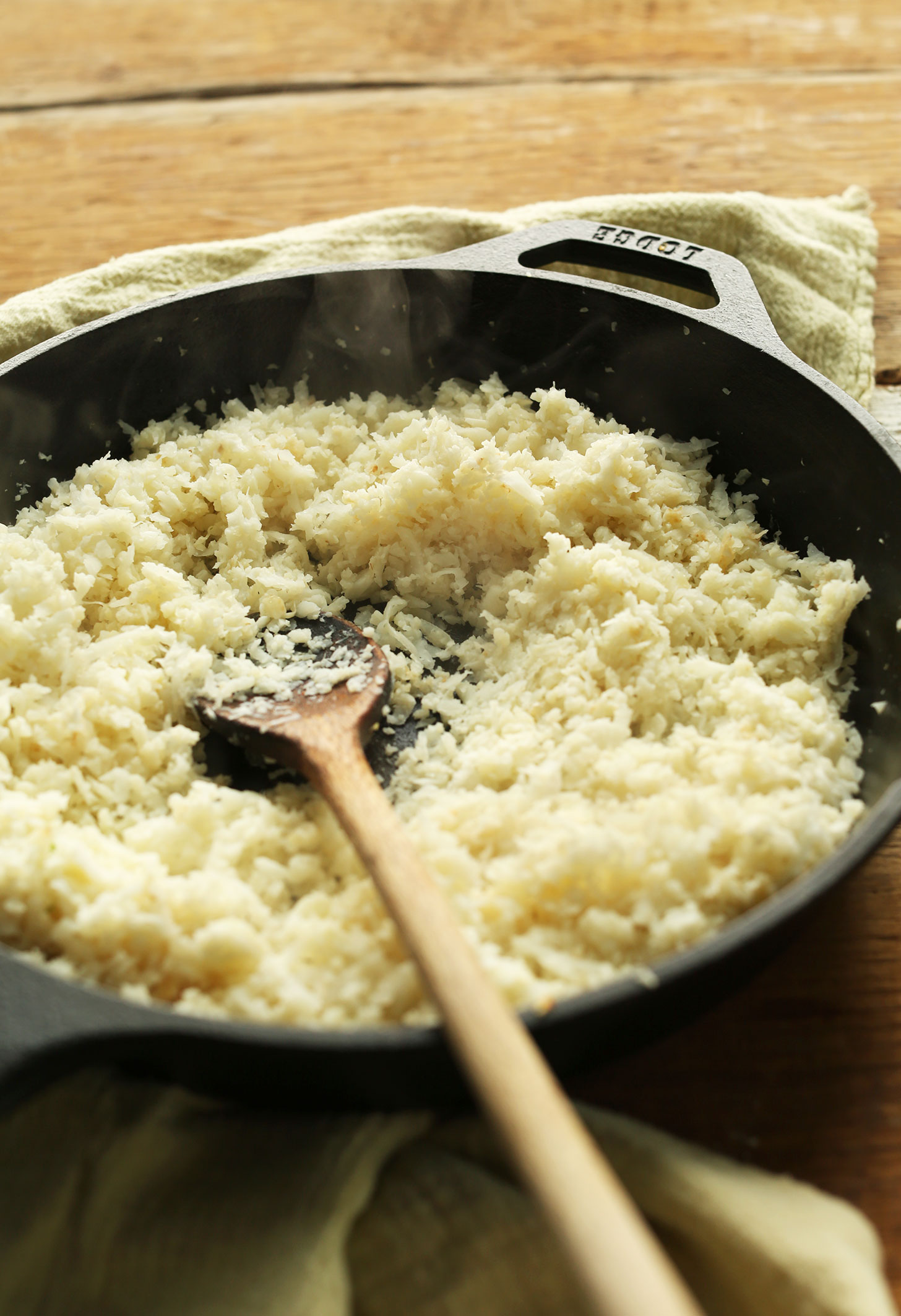 Wooden spoon in a cast-iron skillet of cauliflower rice