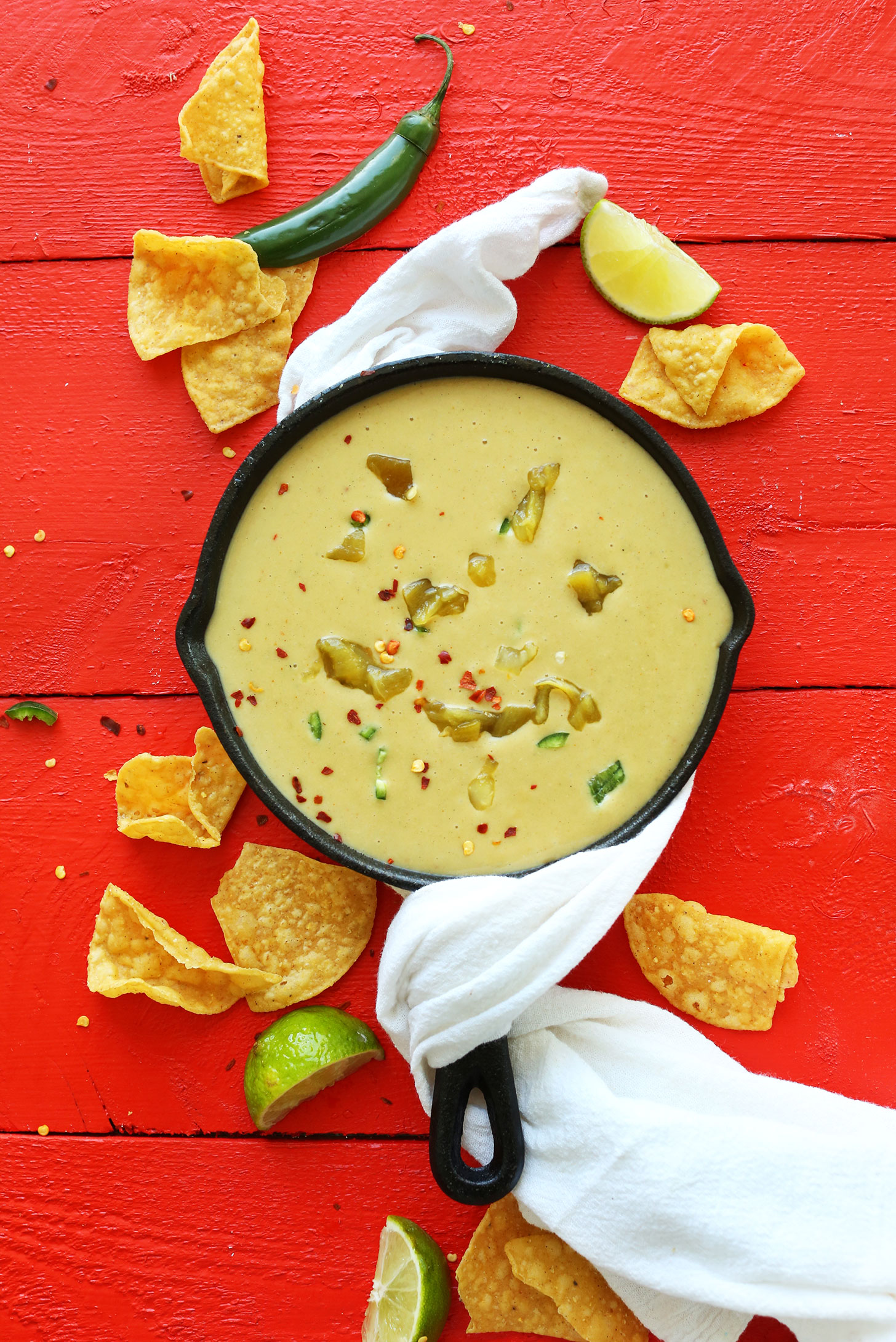 Cast-iron skillet filled with our Vegan Green Chili Queso surrounded by tortilla chips
