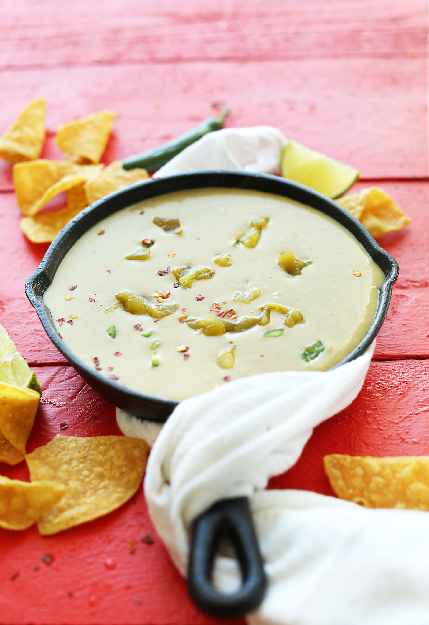 Tortillas chips and a cast-iron skillet filled with Green Chili Queso for the perfect vegan appetizer