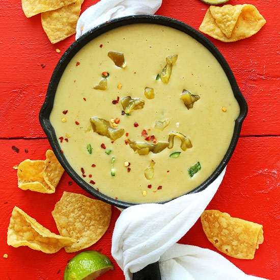 Skillet filled with Vegan Green Chili Queso surrounded by tortilla chips