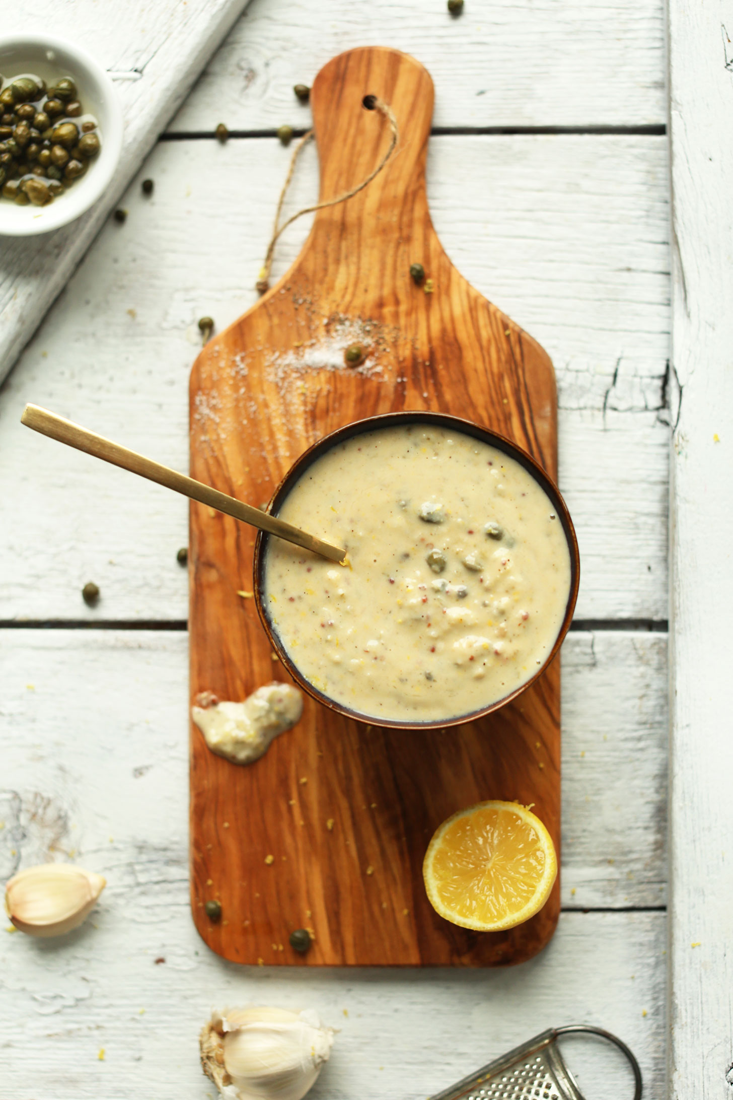 Bowl of our easy vegan caesar dressing recipe on a wood board