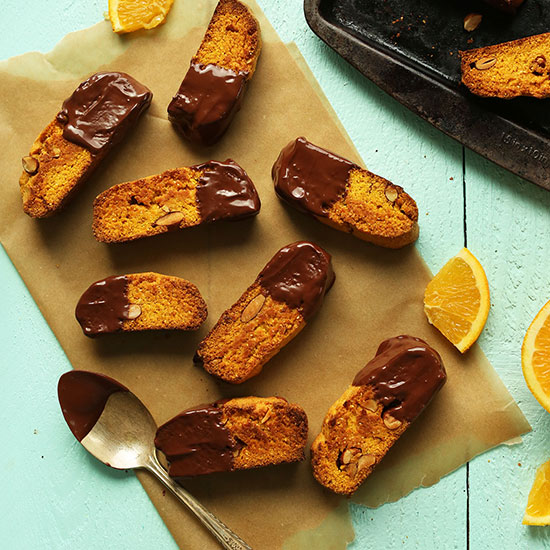 Parchment paper filled with Orange Almond Vegan Biscotti dipped in dark chocolate