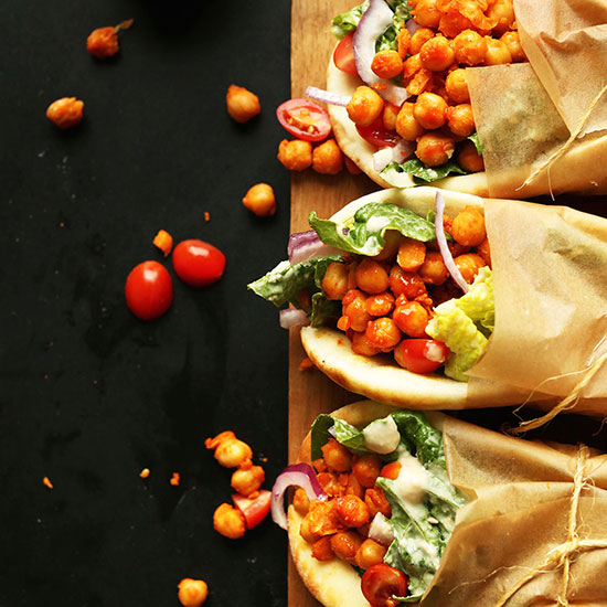 Cutting board with three Spicy Chickpea Wraps tied with parchment paper and twine