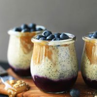 Three jars of Peanut Butter and Jelly Chia Pudding topped with fresh blueberries