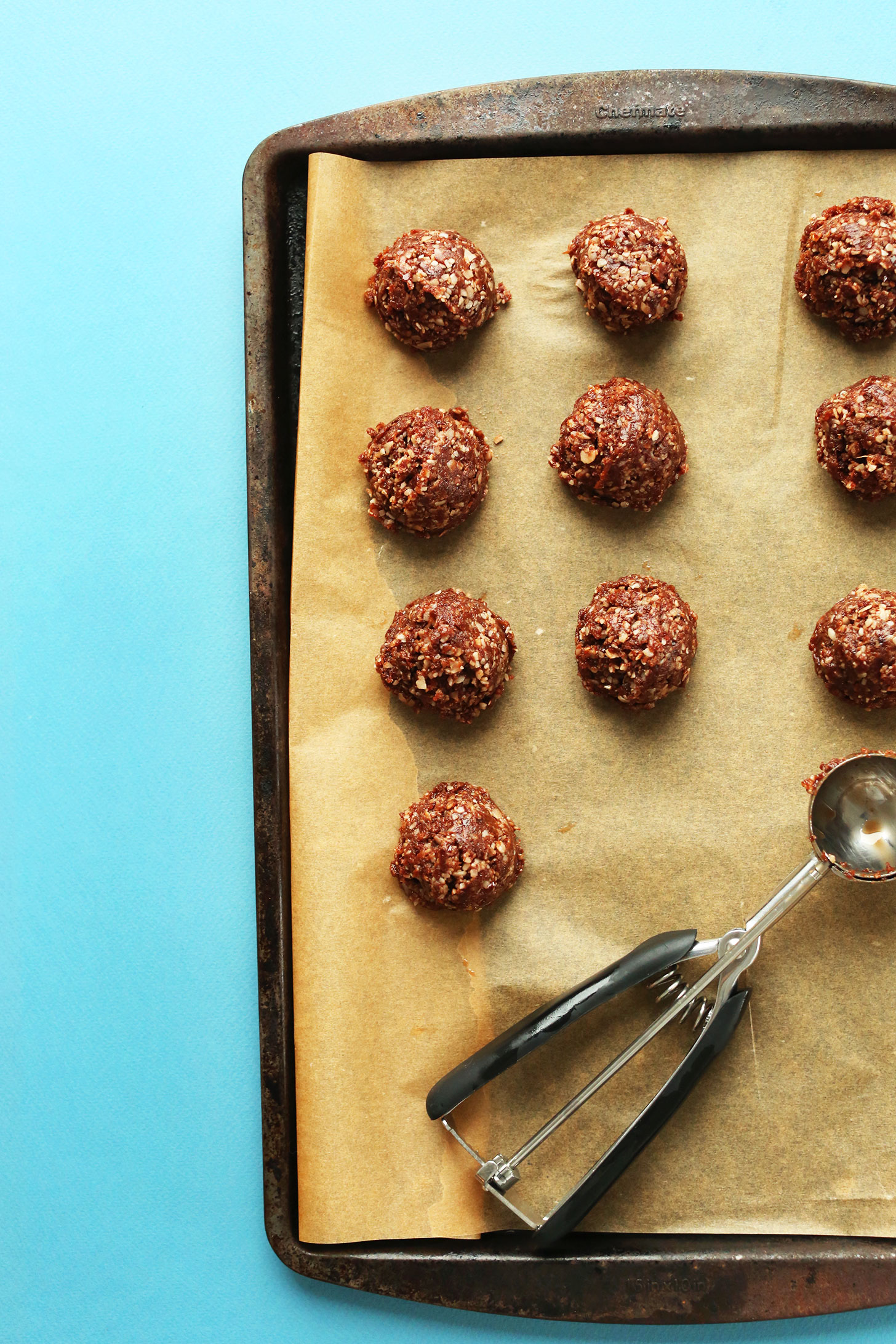Scooping Raw Double Chocolate Macaroon batter onto a parchment-lined baking sheet