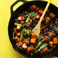 Wooden spoon resting on a skillet filled with our General Tso's Tofu Stir Fry recipe