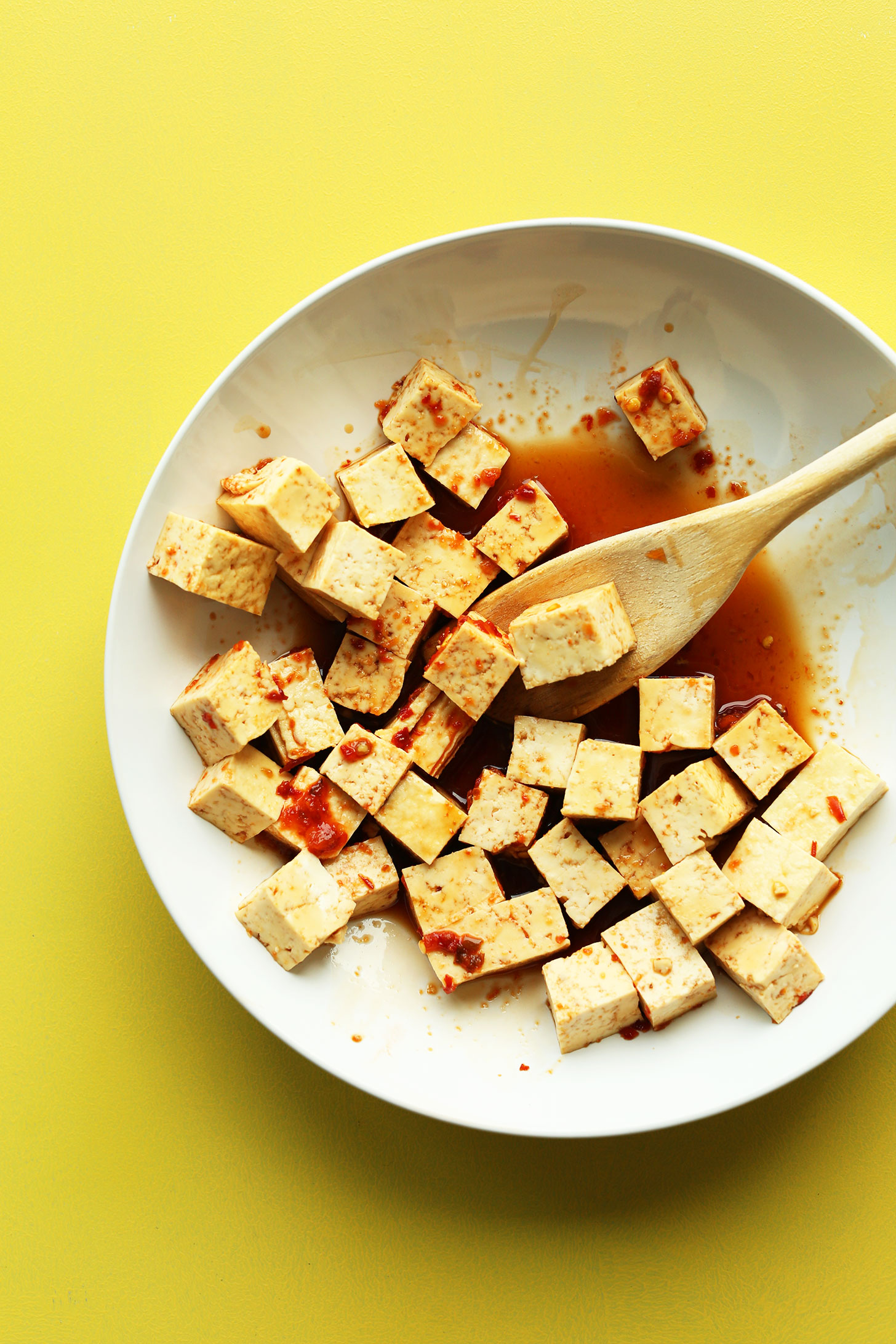 Marinating cubes of tofu in gluten-free vegan sweet and spicy sauce
