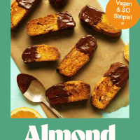 Chocolate-dipped vegan orange almond biscotti on a piece of parchment paper