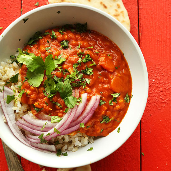 Bowl of Red Lentil Curry and brown rice topped with red onion and cilantro
