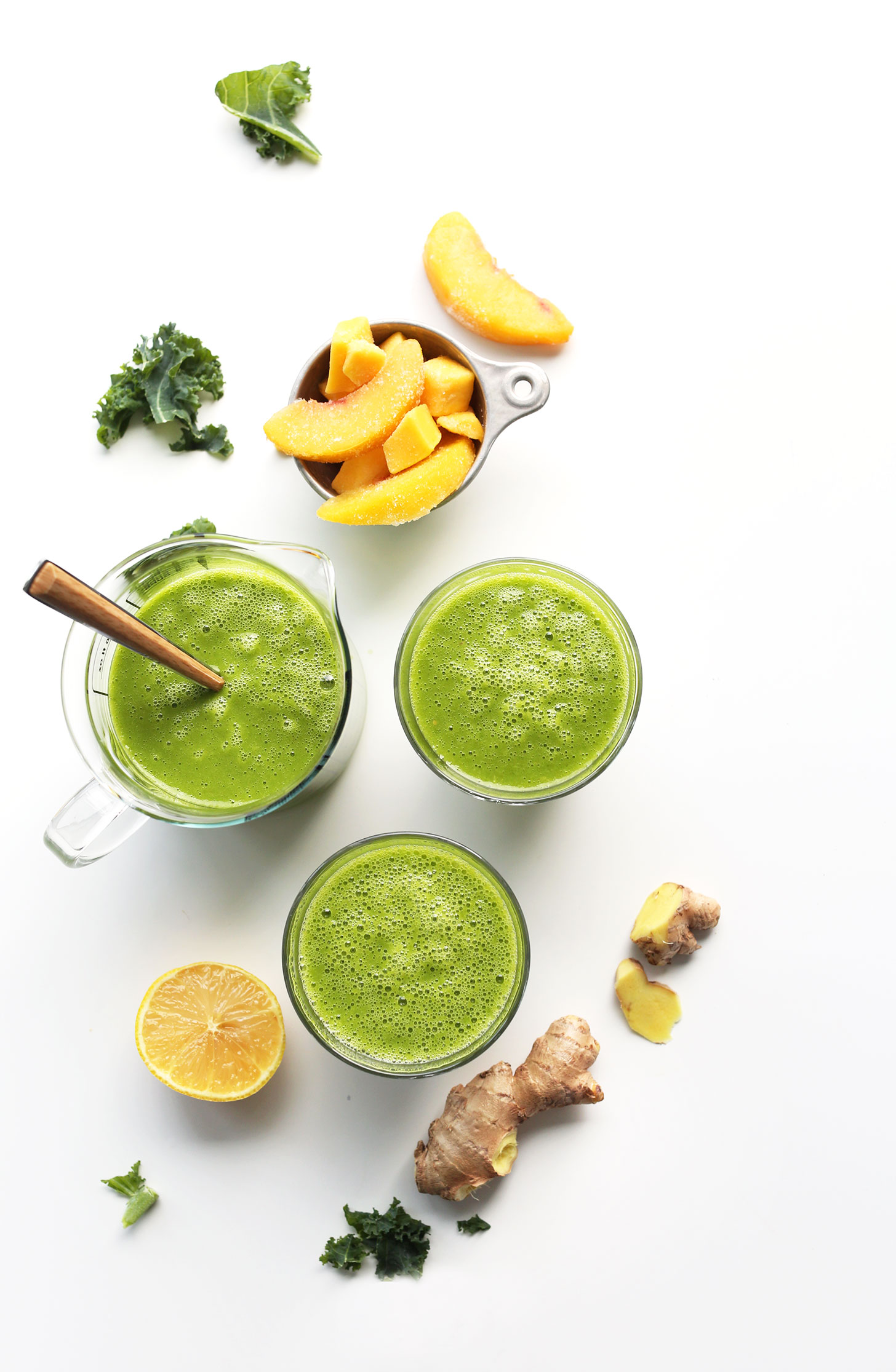 Glasses filled with our Mango Ginger Kale Smoothie recipe and ingredients used to make it