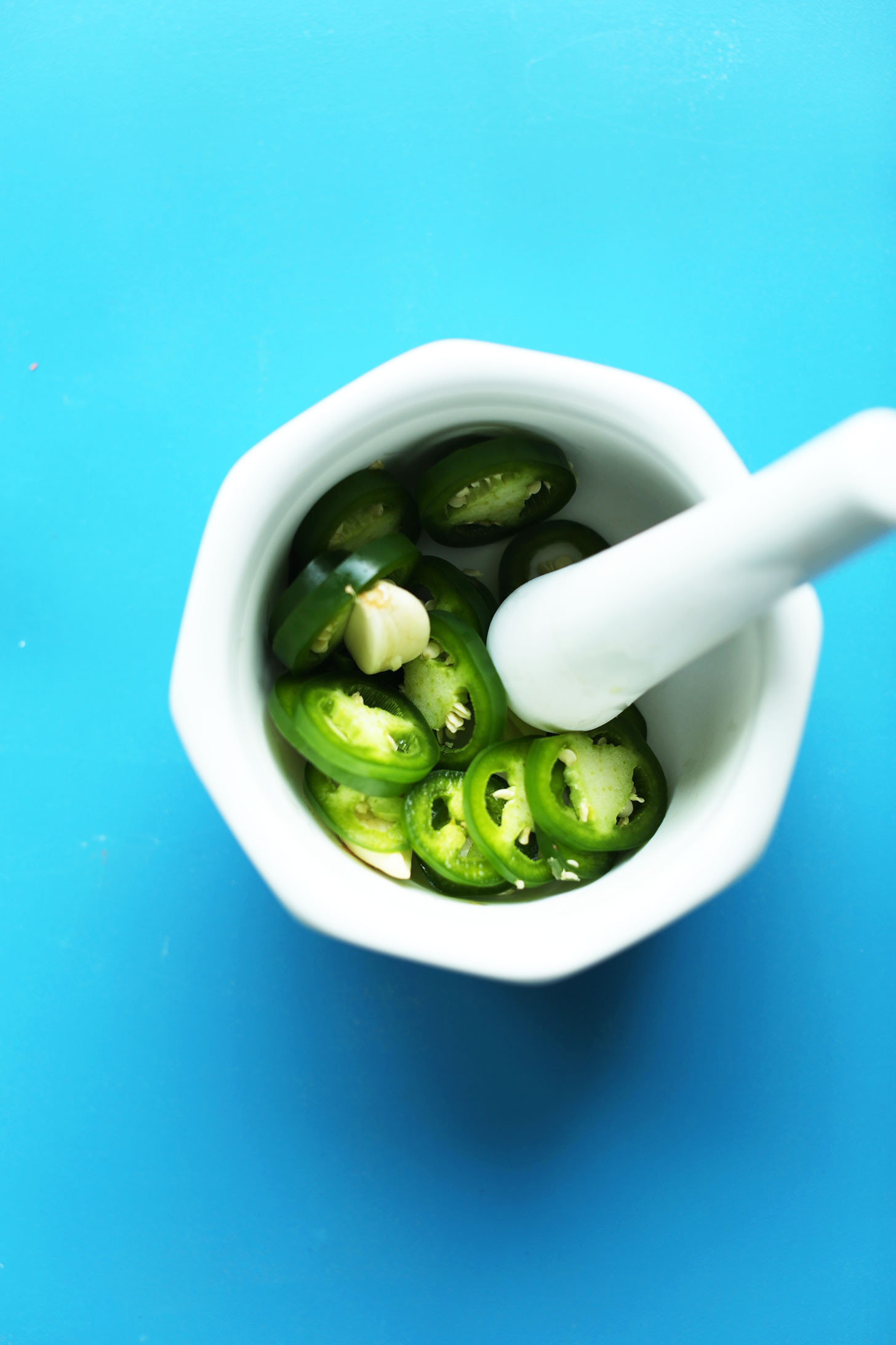 Mortar and pestle with sliced jalapenos for making our healthy chili recipe
