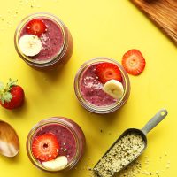 Three small jars of Banana Berry Hempseed Pudding topped with sliced fruit