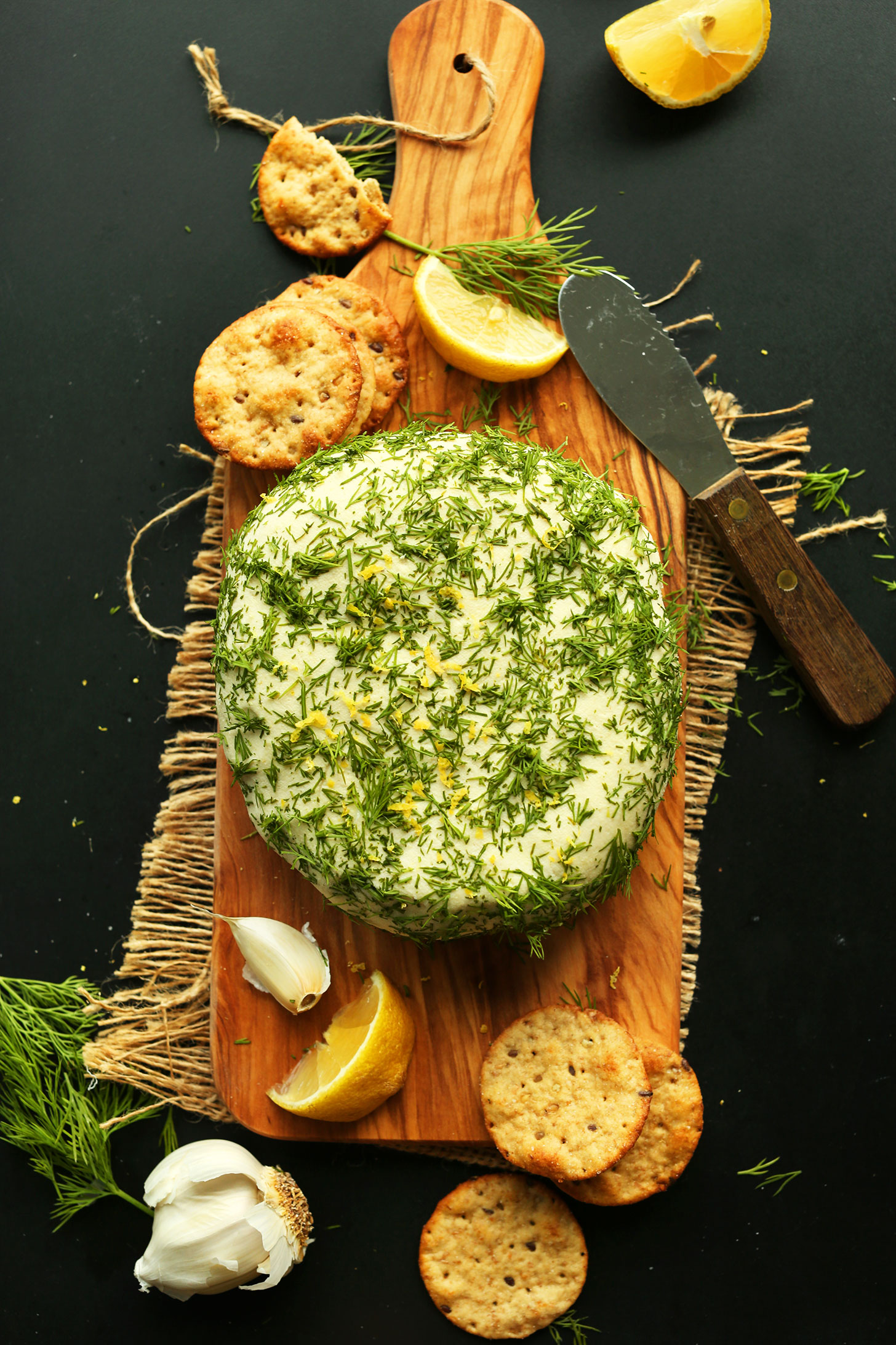 Wood cutting board with crackers and our Easy Creamy Vegan Cheese wheel