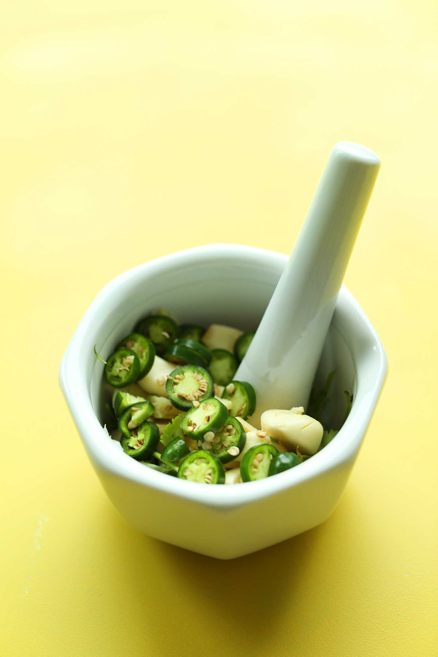 Mortar and pestle with jalapenos and garlic for making our easy chana masala recipe